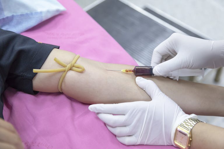 Warum deine Blutwerte normal – aber nicht optimal sind 2 A medical professional takes a blood sample from a patient for testing.